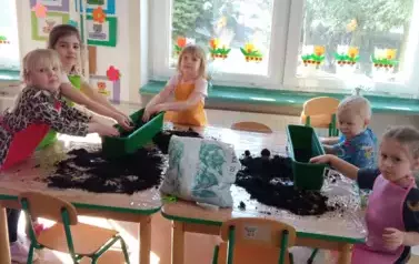 dzieci rozsypuja ziemie do doniczek