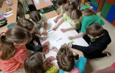 Dzieci pracują w grupie nad plakatem