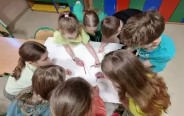 Dzieci pracują w grupie nad plakatem