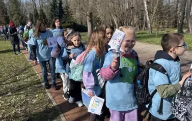 uczniowie maszerujący wok&oacute;ł stawu z niebieską wstęgą &ndash; symbolem solidarności z osobami ze spektrum autyzmu