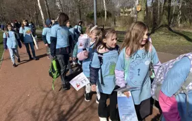 uczniowie maszerujący wok&oacute;ł stawu z niebieską wstęgą &ndash; symbolem solidarności z osobami ze spektrum_autyzmu