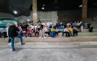 Grupa dzieci siedząca na kamiennych schodach.