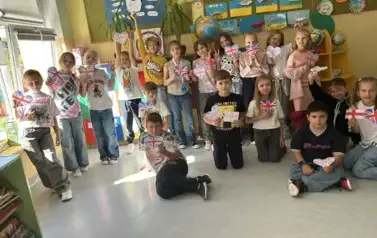 uczniowie klasy trzeciej pozujący do zdjęcia z flagami Wielkiej Brytani w kształcie serc
