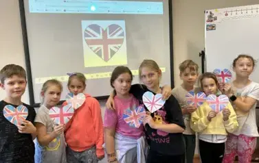 uczniowie klasy trzeciej pozujący do zdjęcia z flagami Wielkiej Brytani w kształcie serca