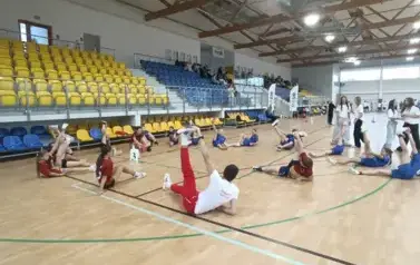 Uczniowie wykonują ćwiczenia rozciągające z mistrzem olimpijskim, lekkoatletą, Dariuszem Kowalukiem