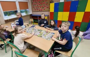 dzieci siedzą przy stoliku i grają w plansz&oacute;wki