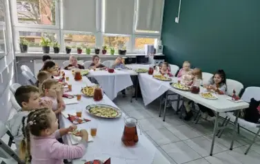 cała grupa siedzi przy stole i zajada zrobione tartinki