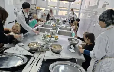 dzieci wybierają łyżkami serek z pojemniczk&oacute;w do misek