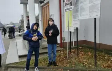 dw&oacute;ch chłopc&oacute;w z puszką kwestują przy kościele na cmentarzu