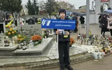 chłopiec stoi przed grobami z banerem TPZ