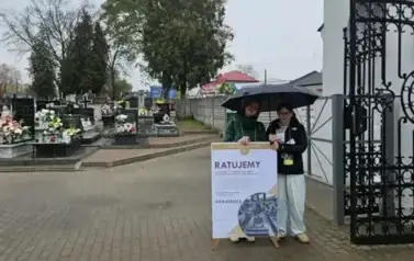 dwie uczennice z klasy 6a zbierają datki na renowację zabytkowych grob&oacute;w przy bramie wejściowej na cmentarz