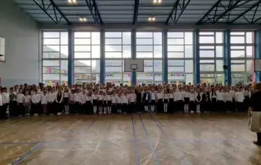 uczniowie klas 1 - 8 ustawia się w sali gimnastycznej do wsp&oacute;lnego śpiewania