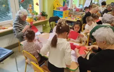 przedszkolaki z gości siedzą przy stolikach i wykonują kotyliony