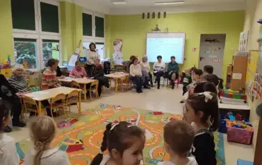 dzieci śpiewają piosenkę, seniorzy w sali ich słuchają