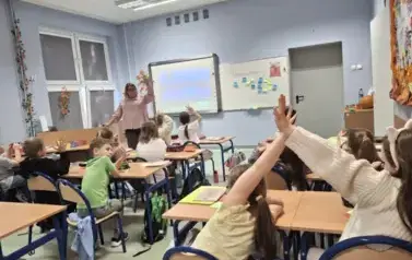 Uczniowie klasy drugiej w ławkach w trakcie zajęć edukacyjnych z pedagogiem specjalnym