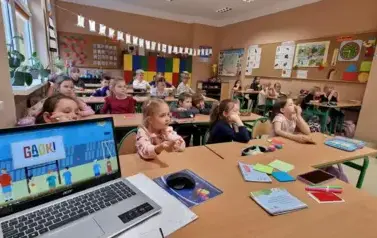 Uczniowie klasy pierwszych w ławkach w trakcie zajęć edukacyjnych z pedagogiem specjalnym