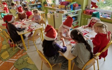 Dzieci przy stolikach ozdabiają skarpety od Mikołaja 