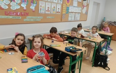 uczniowie w ławkach pracują z plasteliną