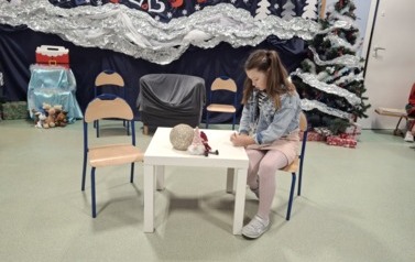 Uczennica z klasy 2A występująca w roli dziewczynki piszącej list do Świętego Mikołaja podczas inscenizacji dla babć i dziadk&oacute;w