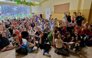 dzieci siedzą na korytarzu i jedzą pączki