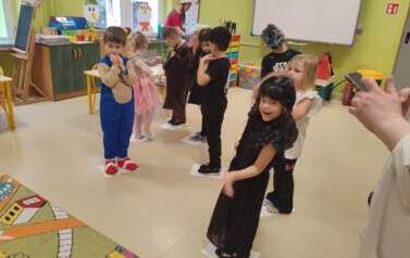 przedszkolaki tańczą stojąc na gazetach