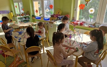 Dzieci w grupach przygotowują stroiki przyklejając do gałązek kolorowe paski bibuły 