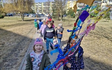 Grupa spaceruje ze stroikami uliczkami osiedla w poszukiwaniu oznak wiosny