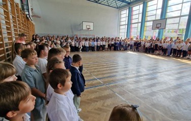 uczniowie klas 1-4  ustawieni w sali gimnastycznej podczas uroczystości rozpoczęcia nowego roku szkolnego