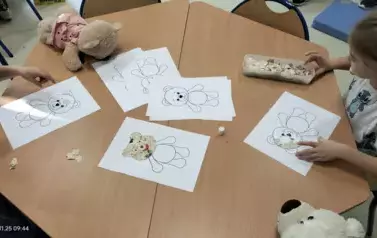 Dzieci wyklejają misia