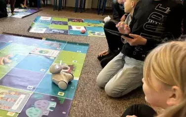 grupa uczni&oacute;w w czasie zabawy robotem edukacyjnym