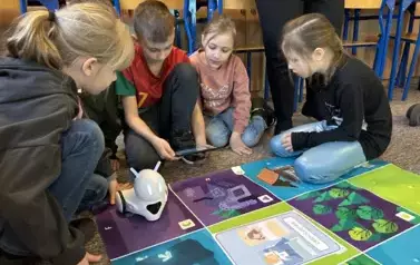 grupa uczni&oacute;w uczy się obsługiwać roboty edukacyjne