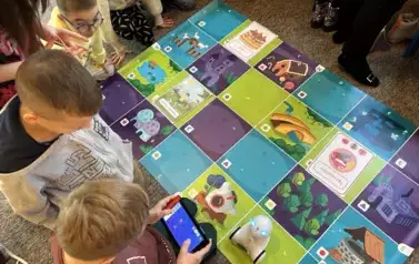 grupa uczni&oacute;w w czasie zabawy robotem edukacyjnym