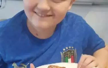 chłopiec z kawałkiem pizzy na talerzu