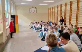 uczennica recytująca wiersz stoi przed publicznością oraz komisją konkursową