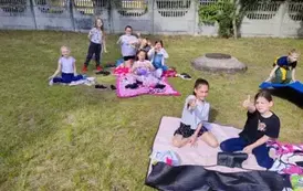 Uśmiechające się dzieci, siedzące na kocach na boisku szkolnym 