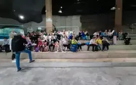 Grupa dzieci siedząca na kamiennych schodach.