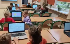 uczniowie projektują plakaty przy komputerach