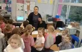 uczniowie zgromadzeni wok&oacute;ł pani bibliotekarki