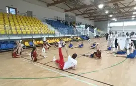 Uczniowie wykonują ćwiczenia rozciągające z mistrzem olimpijskim, lekkoatletą, Dariuszem Kowalukiem