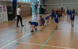 Grupa uczni&oacute;w pokonuje płotki na r&oacute;żne sposoby z mistrzem olimpijskim, lekkoatletą, Mateuszem Rzeźniczakiem