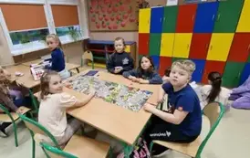 dzieci siedzą przy stoliku i grają w plansz&oacute;wki