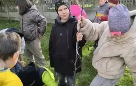Uczniowie klasy 2c wykopują szpadlem dołek na drzewo