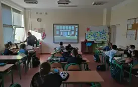 Uczniowie klasy 3d siedzą w szkolnych ławkach i oglądają film edukacyjny