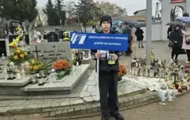 chłopiec stoi przed grobami z banerem TPZ