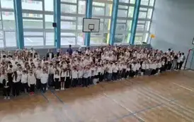 uczniowie klas 1 - 8 zgromadzona w sali gimnastycznej na tle okien