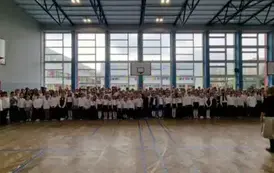 uczniowie klas 1 - 8 ustawia się w sali gimnastycznej do wsp&oacute;lnego śpiewania