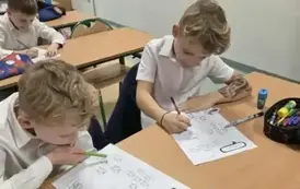 Zdjęcie przedstawia dw&oacute;ch uczni&oacute;w klasy 1b wypełniających karty pracy