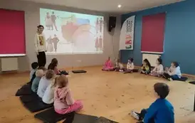 zajęcia w CKD- dzieci siedzą na poduszkach, ogladają prezentację o folklorze