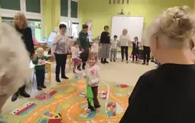 seniorzy z przedszkolakami bawią się w kole w zabawę Mam chusteczkę haftowaną.