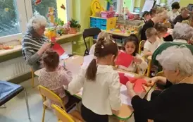 przedszkolaki z gości siedzą przy stolikach i wykonują kotyliony